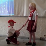 Ein Blindenschüler in Uniform knieht vor einer Mitschülerin. Hält er um ihre Hand an?